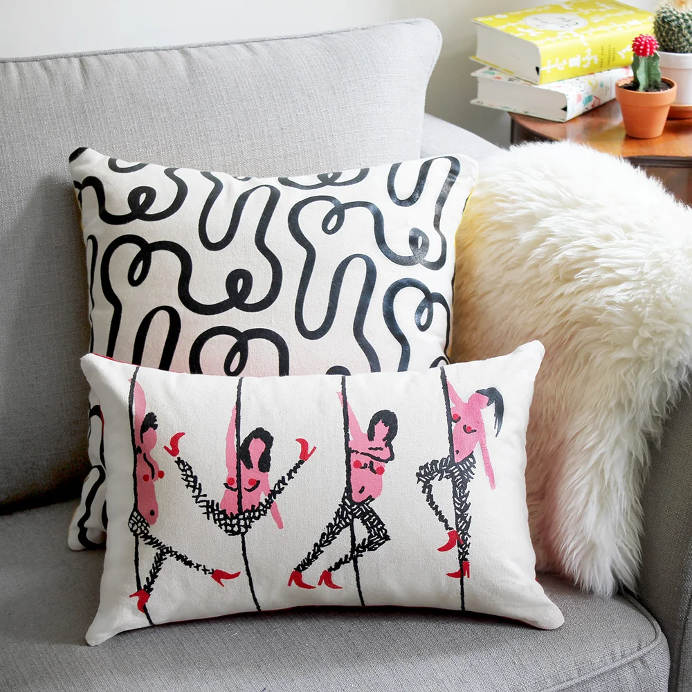 Two soft patterned pillows on a muted gray sofa, accented with a white faux-fur pillow in a calm living-room composition